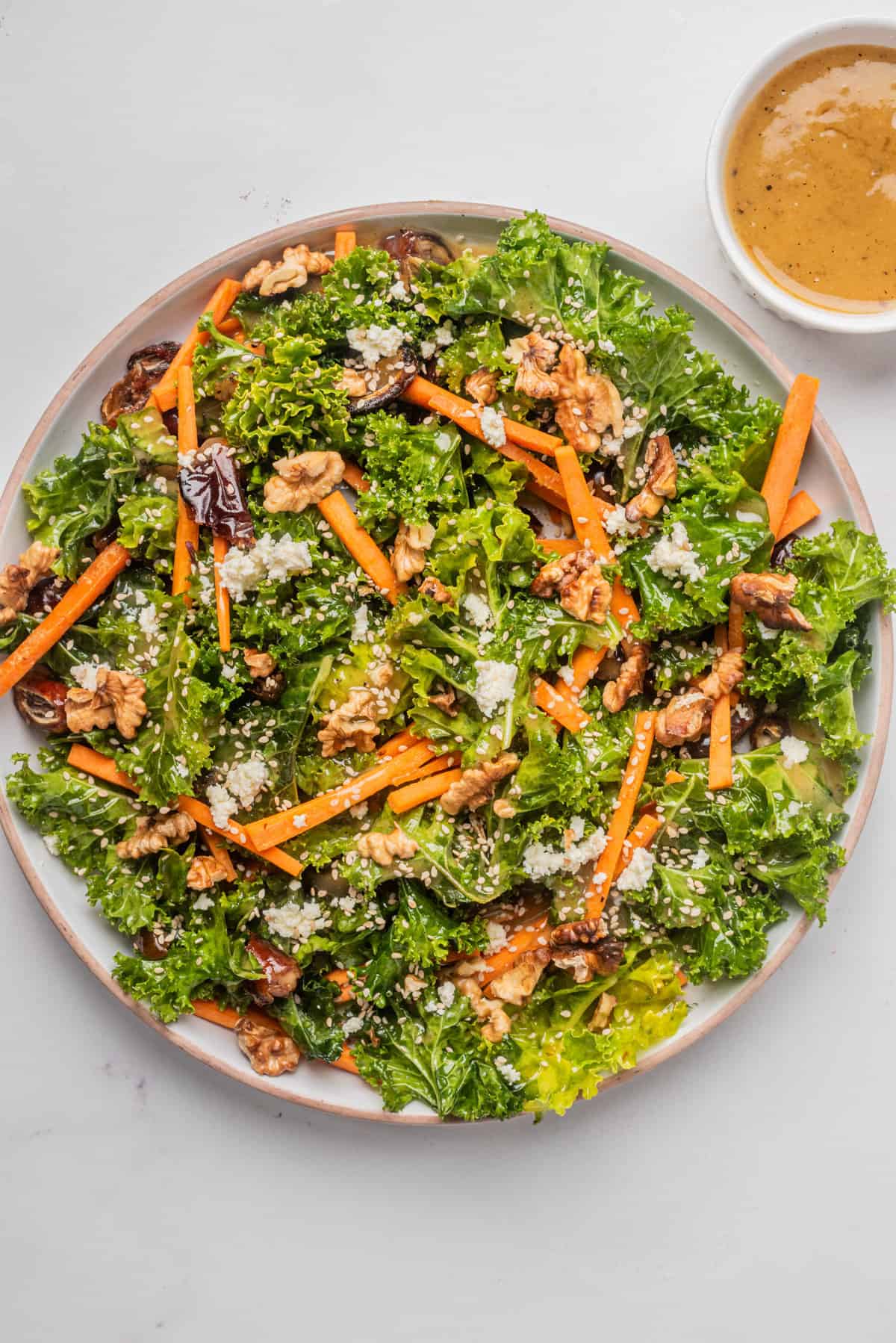 An overhead image of fall kale salad in a serving bowl with dressing on the side.