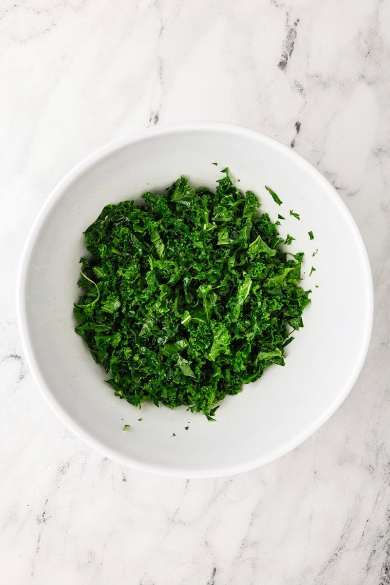 An overhead image of massaging the kale in a bowl.