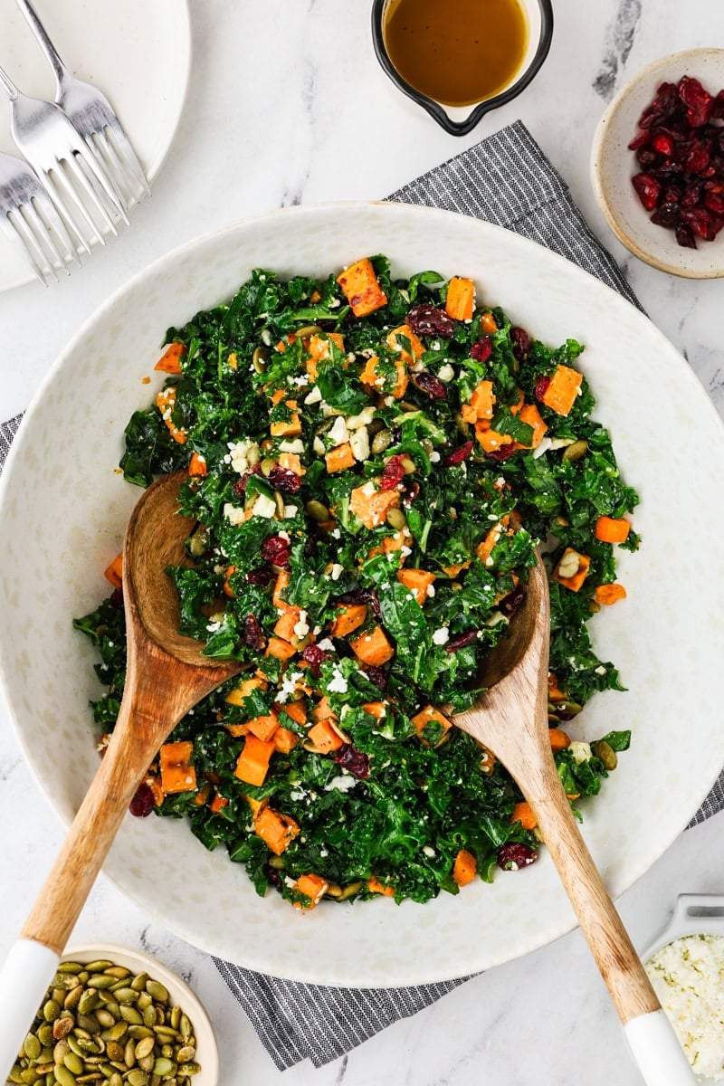 An overhead image of kale sweet potato salad with two wooden serving spoons.