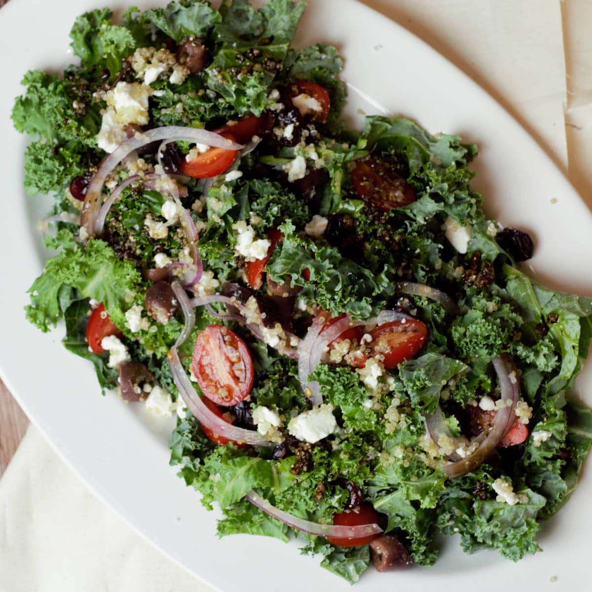 Overhead view of a Greek kale quinoa salad placed on a white plate.