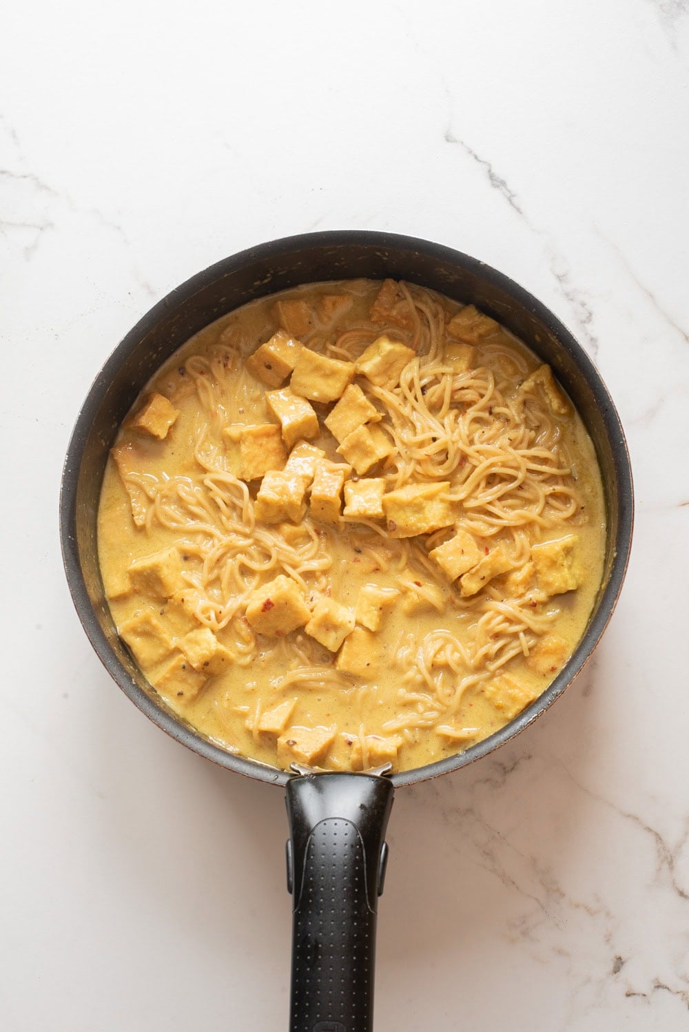 An overhead image of adding vegetable broth to the saucepan.