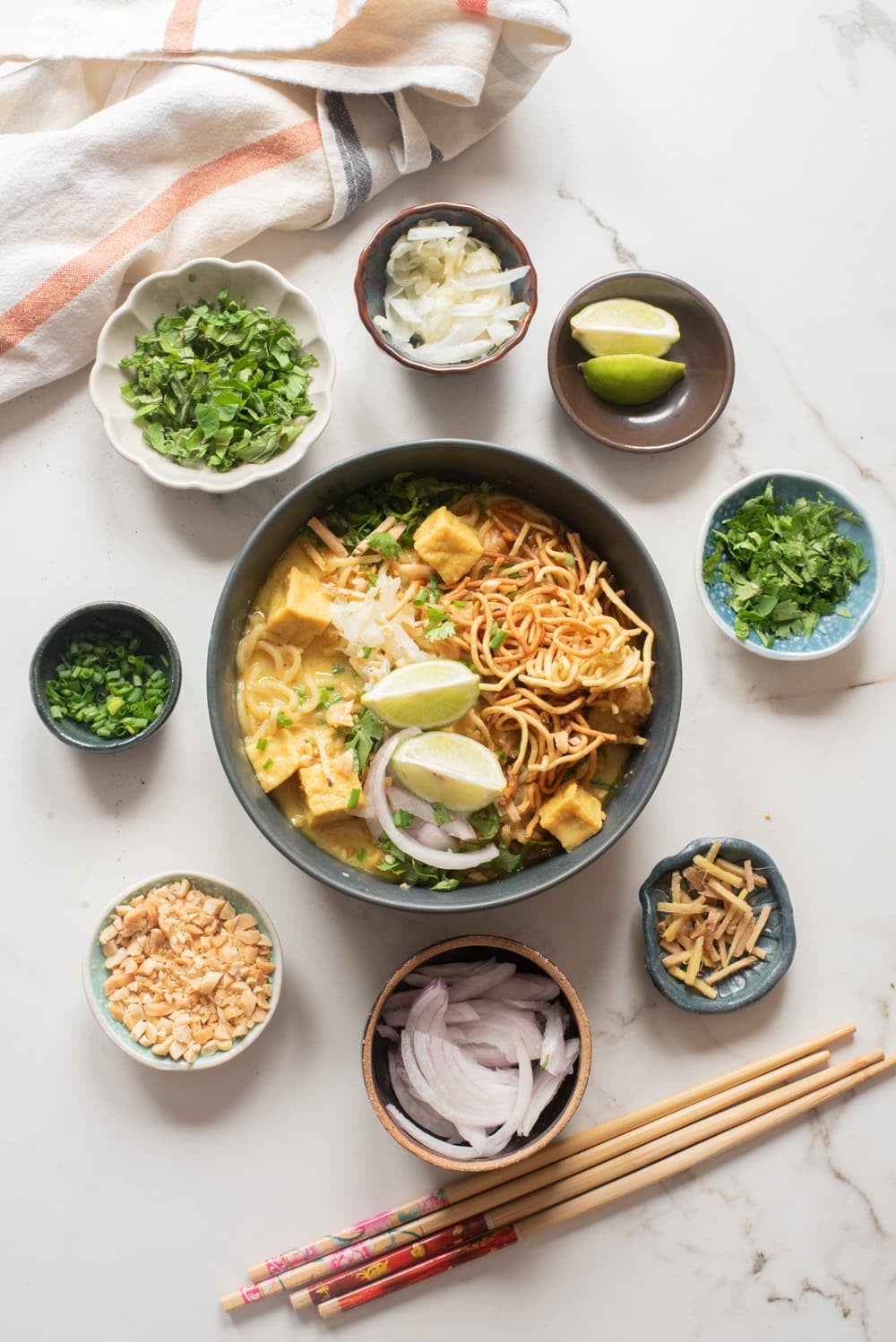 An overhead image of serving the vegetarian khao soi served in a bowl with condiments.