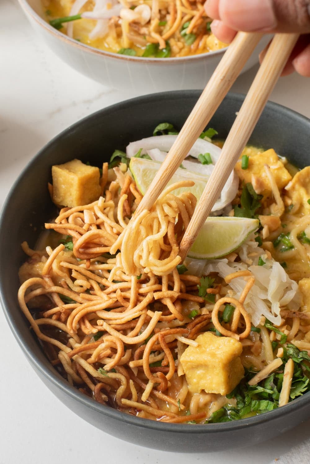 A close up image of khao soi served in a bowl with chopsticks.