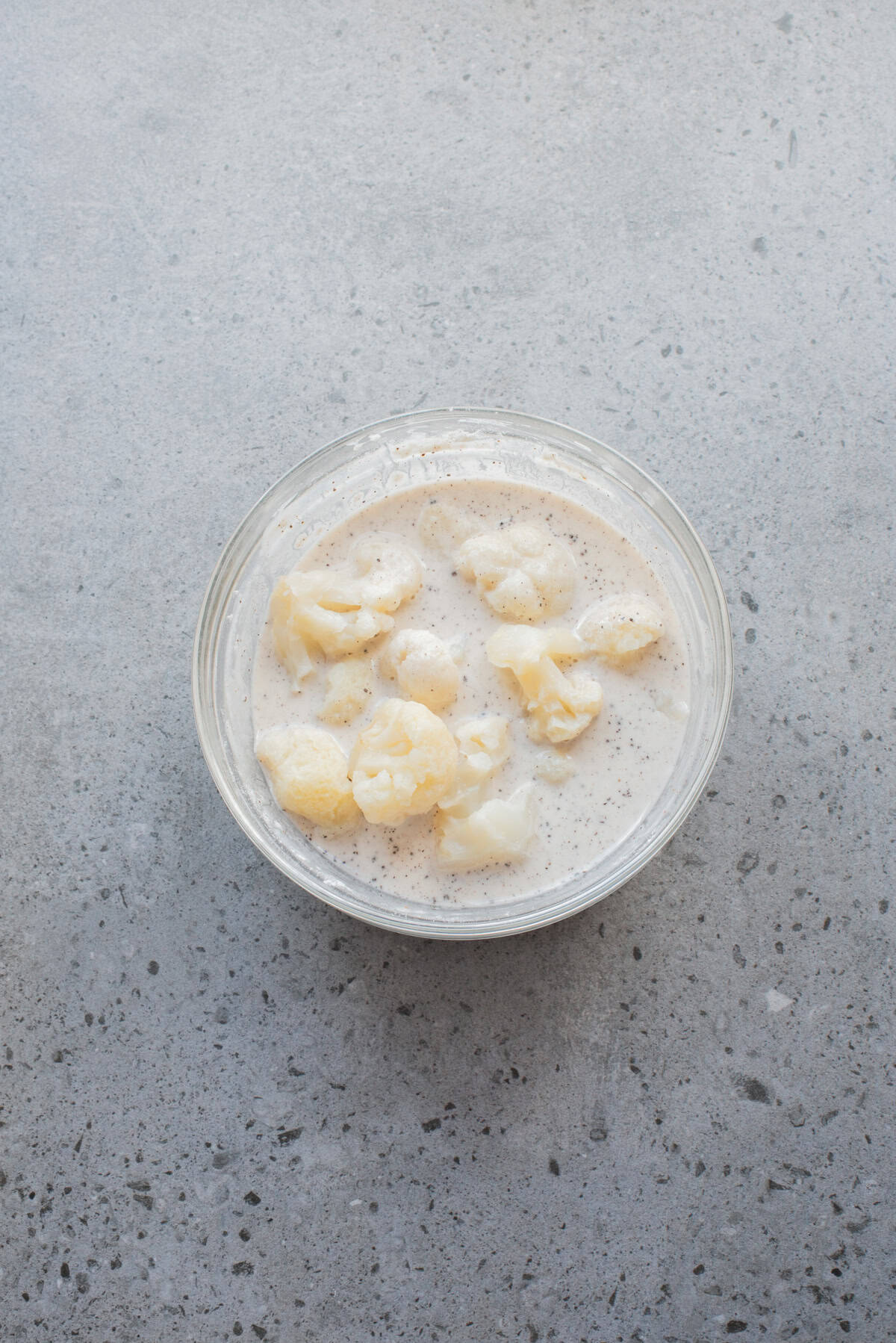 An overhead image of dipping the cauliflower florets in the batter.