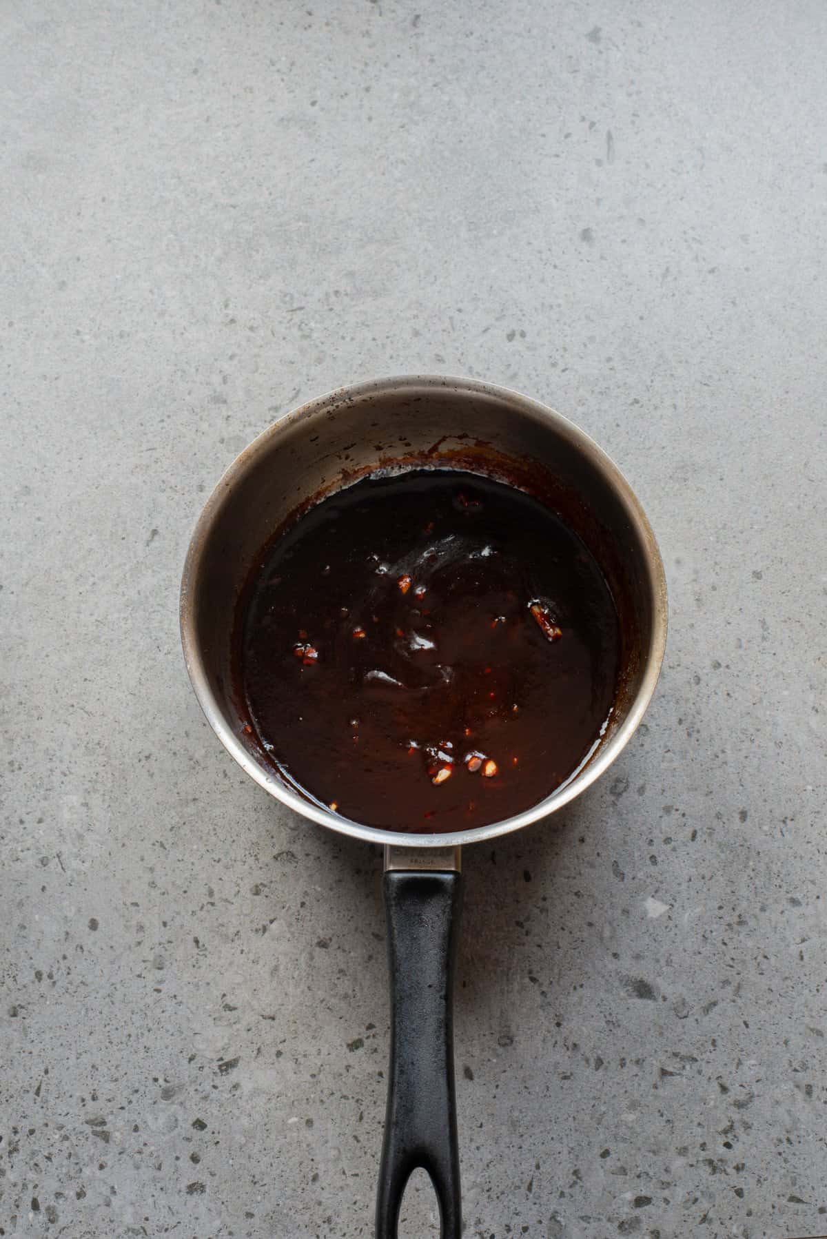 An overhead image of whisking the gochujang sauce together in a saucepan.