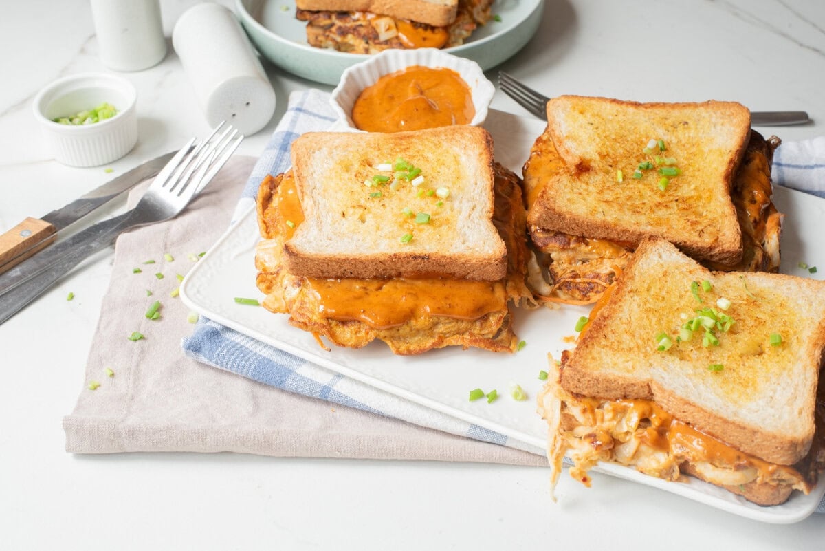 Korean egg sandwiches served on a platter with spicy mayo on the side.