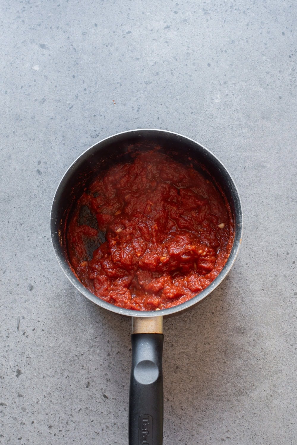 Tomato-vinegar sauce simmering in a saucepan for Egyptian koshari.