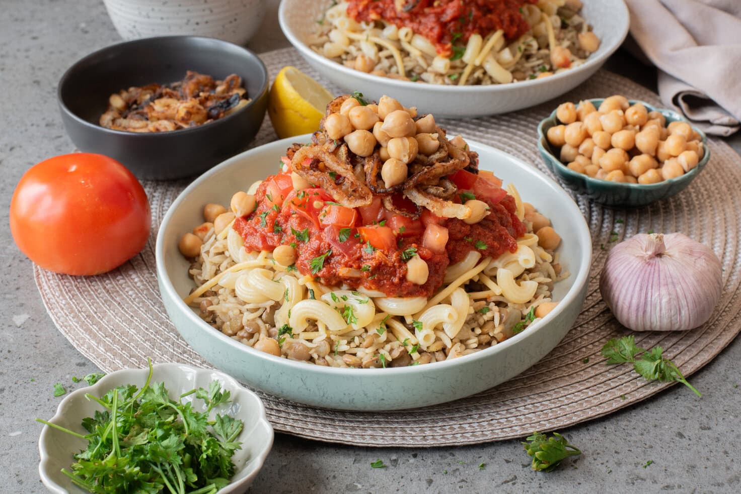 Egyptian koshari served in a bowl with chickpeas, crispy onions, and fresh tomato sauce.