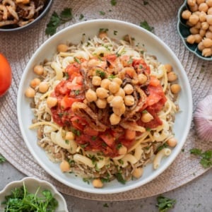 Top view of Egyptian koshari with lentil rice, pasta, chickpeas, crispy onions, and tomato sauces.