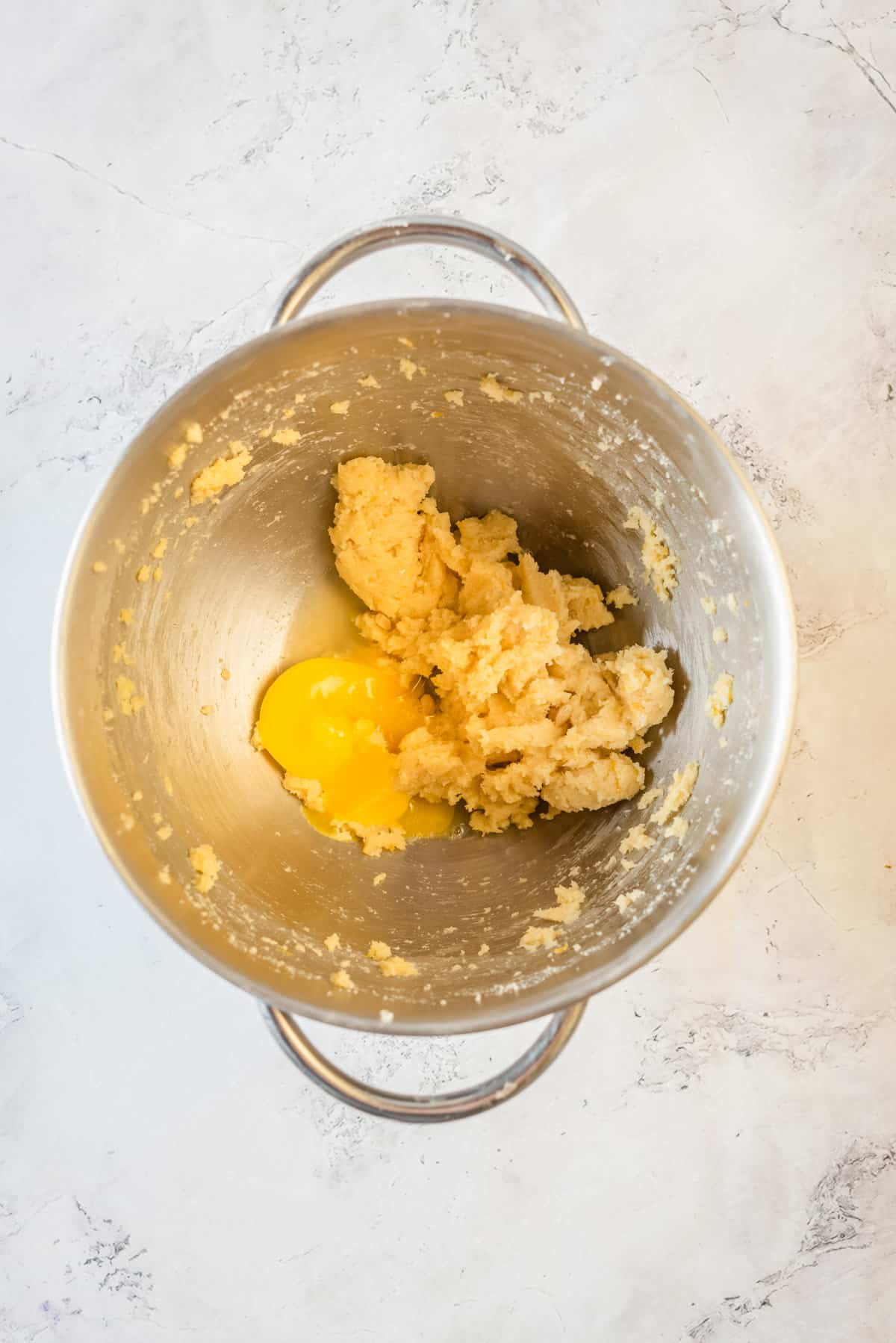 Adding egg yolk to mixed wet ingredients in mixing bowl.