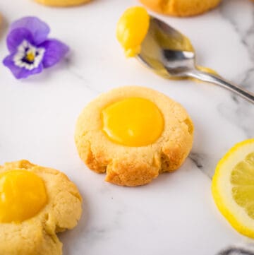 Close up shot of lemon curd cookies with spoon of lemon curd and lavender flower in background.