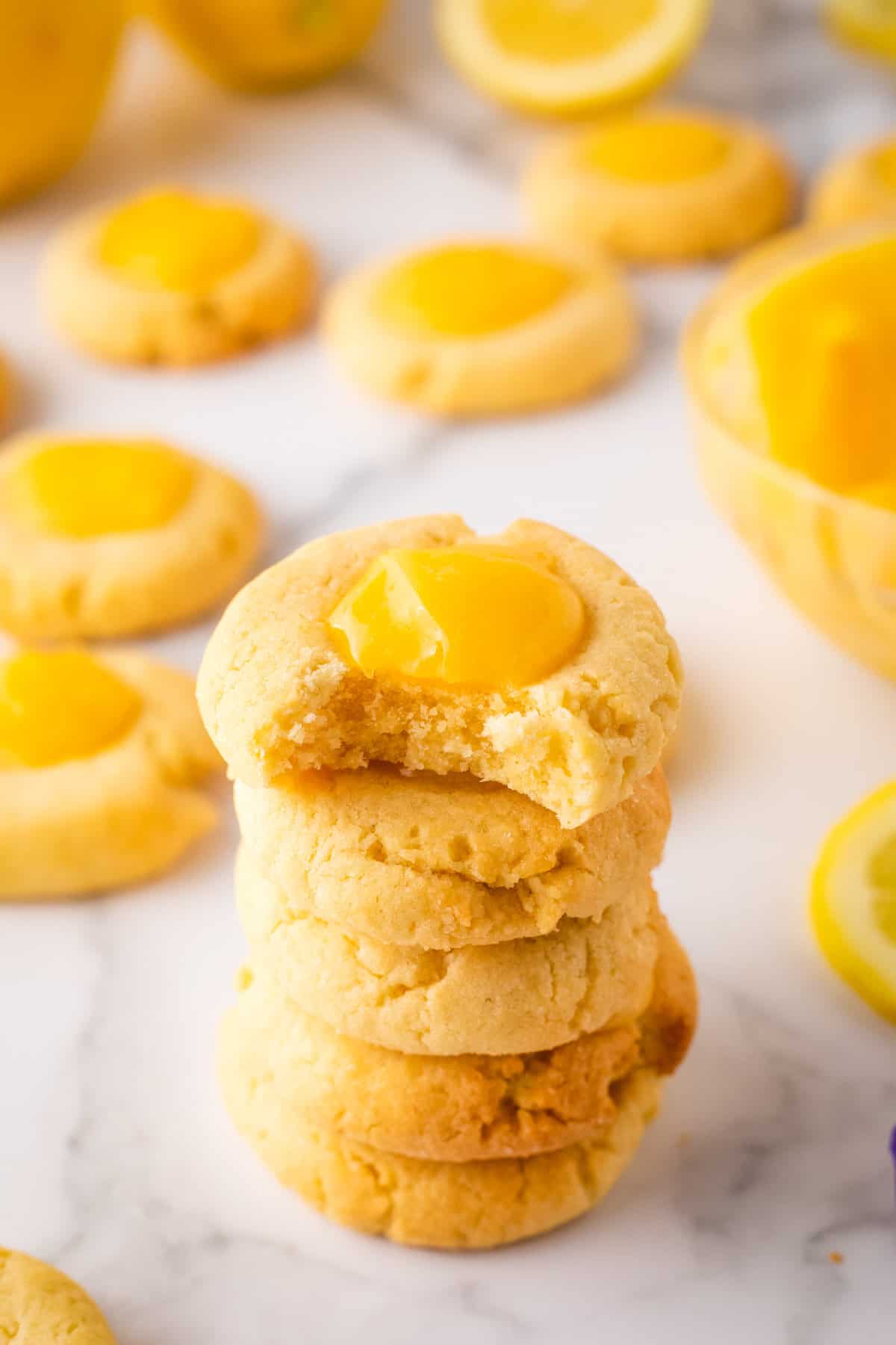 Side angle of stacked lemon curd cookies with one bite taken out of top one.