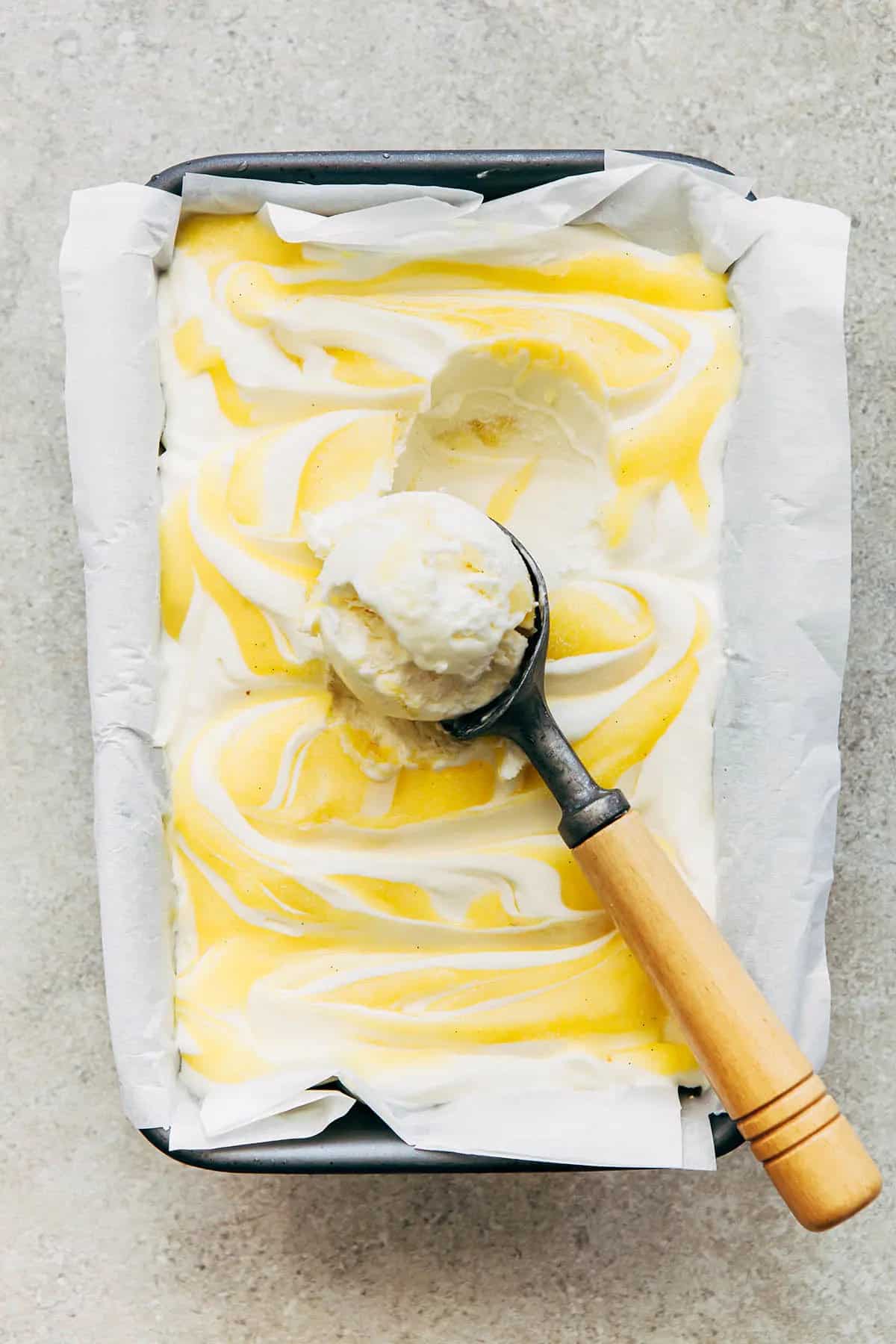 Overhead of lemon curd ice cream with a scoop on top.