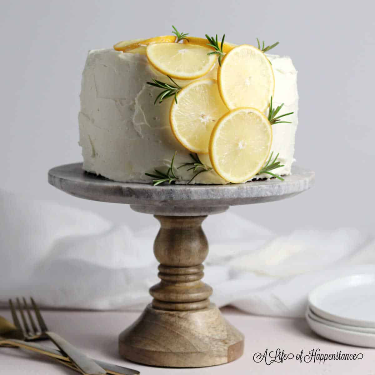 A straight view of lemon rosemary cake in a cake stand.
