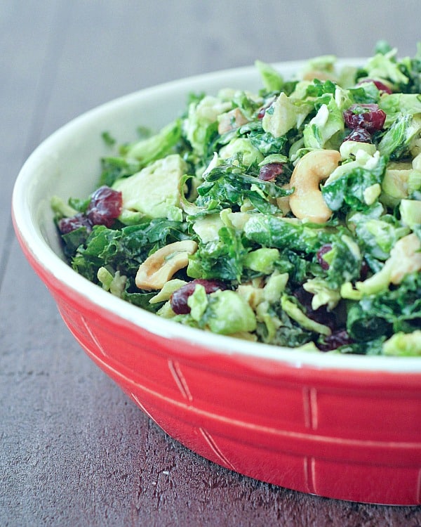 Close-up view of a lemony kale chiffonade salad with dijon vinaigrette on a red and white colored bowl.