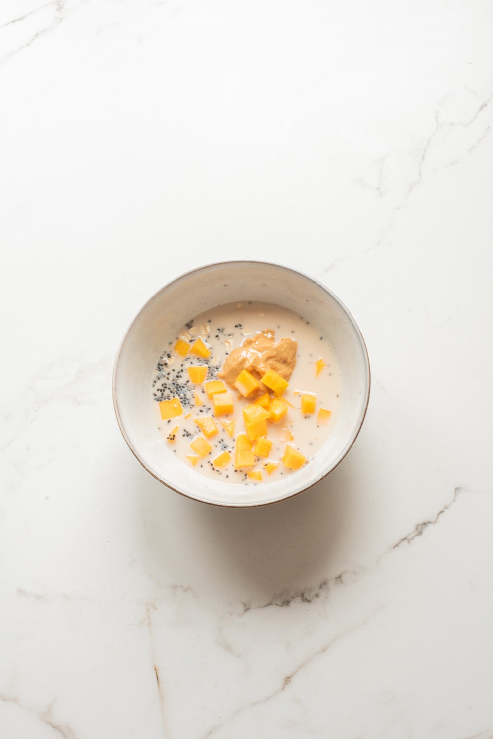 Ingredients of mango coconut chia overnight oats in a bowl.