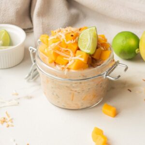 Close up of mango coconut chia overnight oats with toppings in a jar.