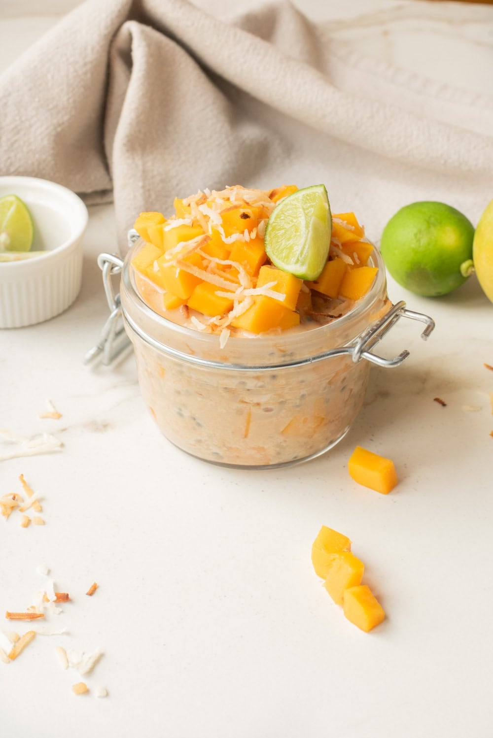 Close up of mango coconut chia overnight oats with toppings in a jar.