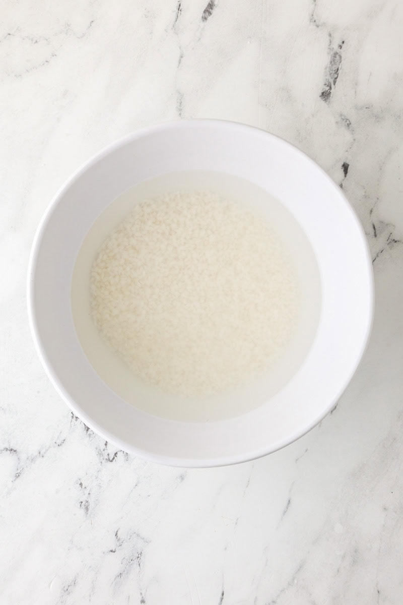 Sticky rice soaking in water in a bowl before cooking.
