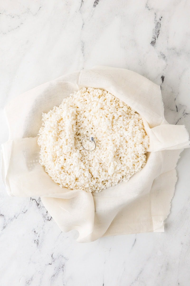 Soaked sticky rice spread on cheesecloth inside a steamer basket.