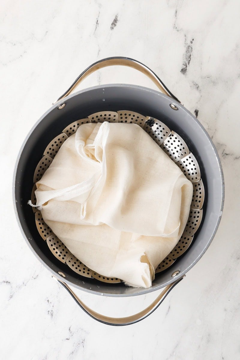 Sticky rice steaming in a metal basket over simmering water.