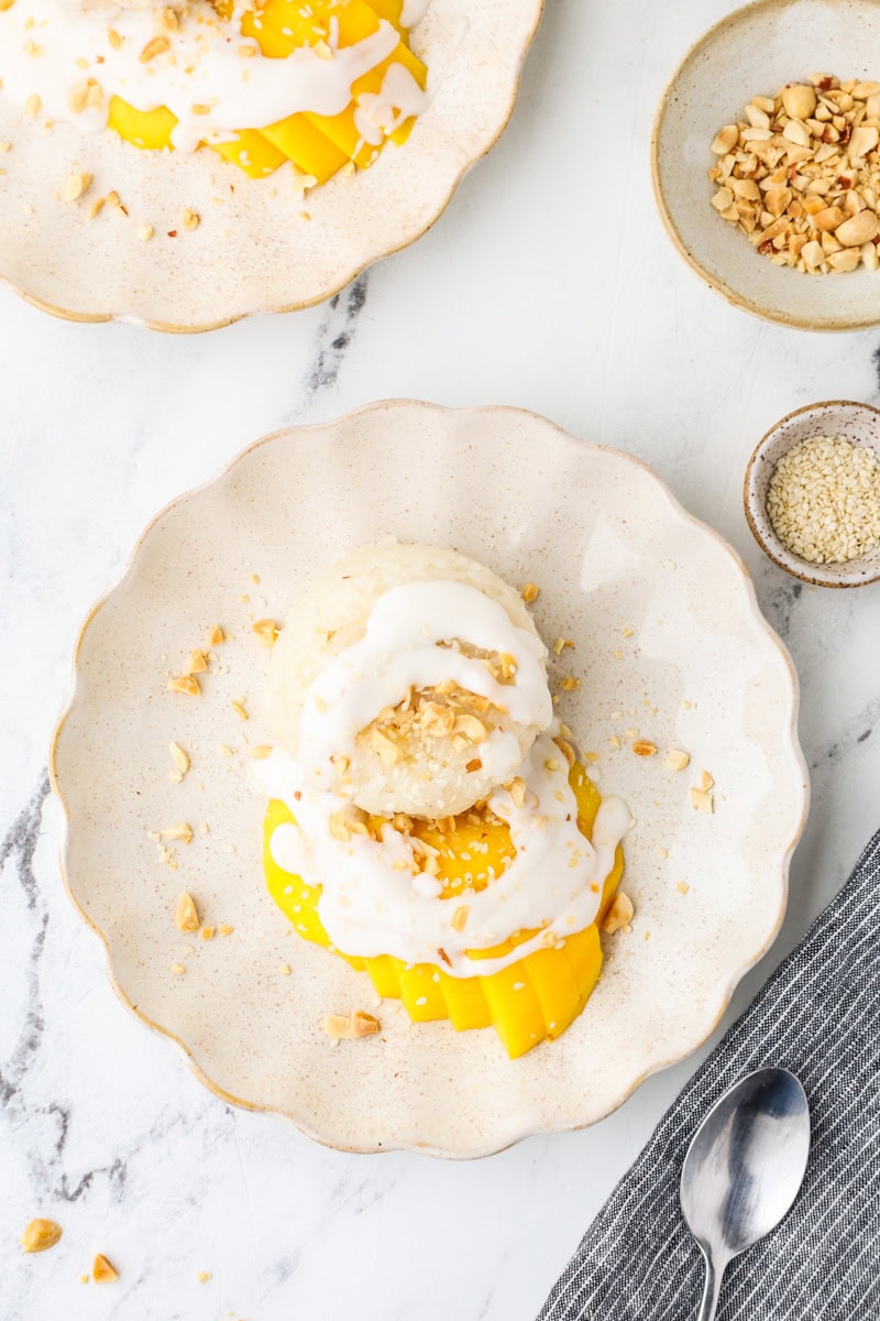 Finished mango sticky rice topped with coconut cream, fresh mango slices, and crushed peanuts.