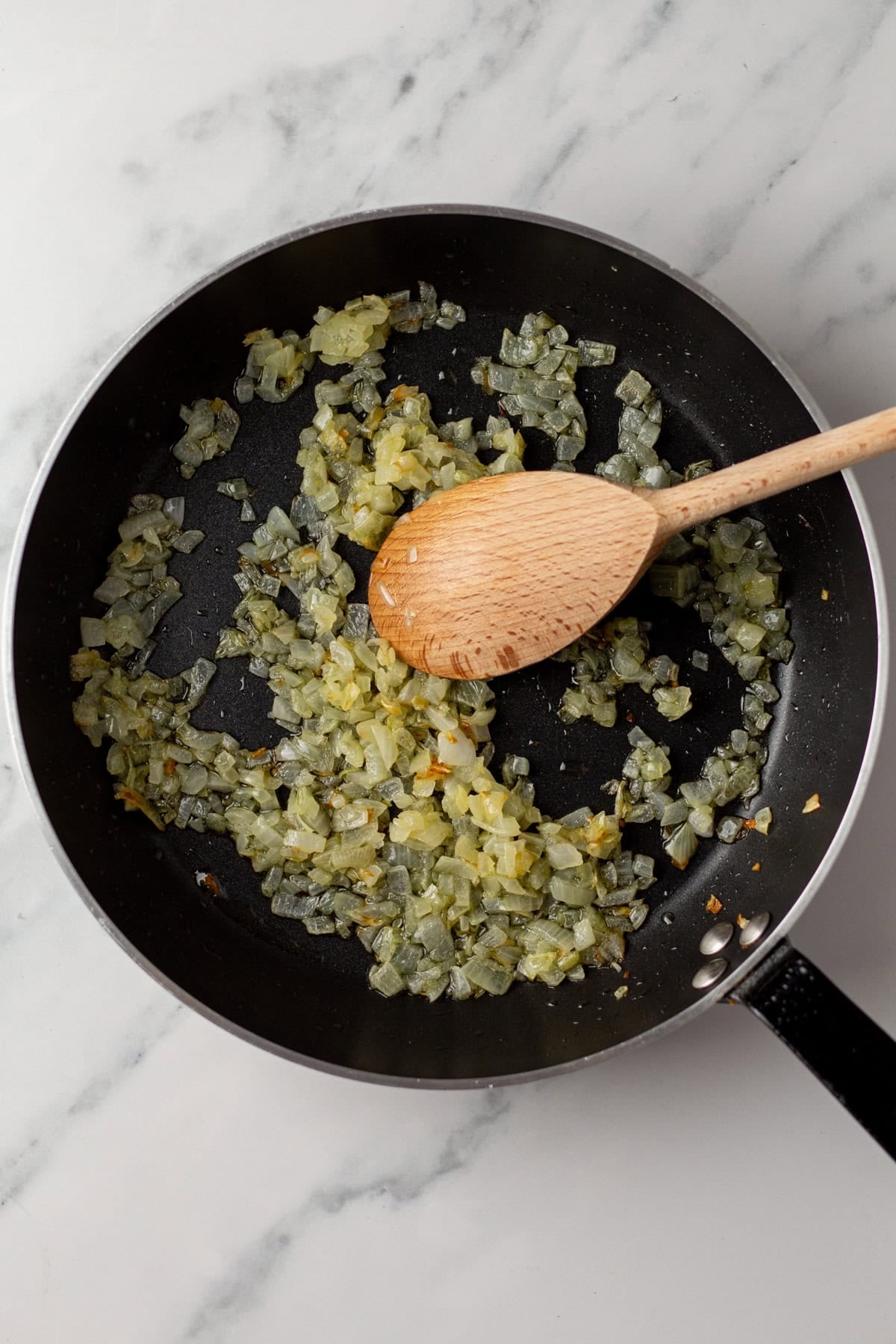 An overhead image of sauteing onions on a skillet.