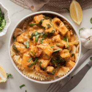Bowl of creamy Marry Me Tofu served over pasta with fresh basil.