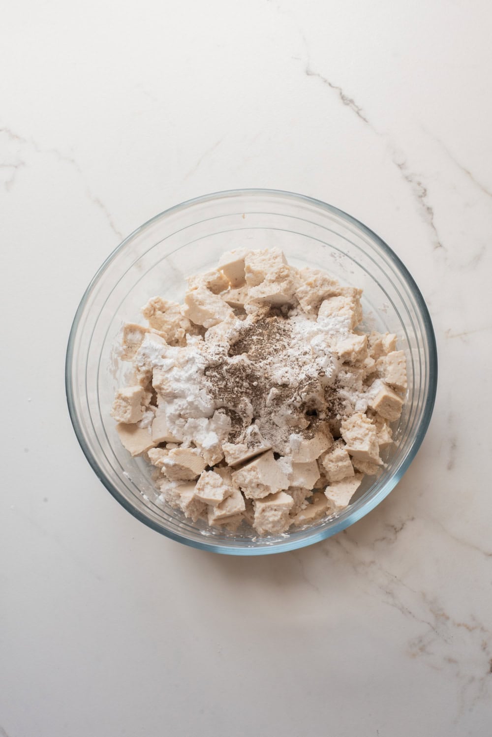 Torn tofu with cornstarch, salt, and pepper before coating.