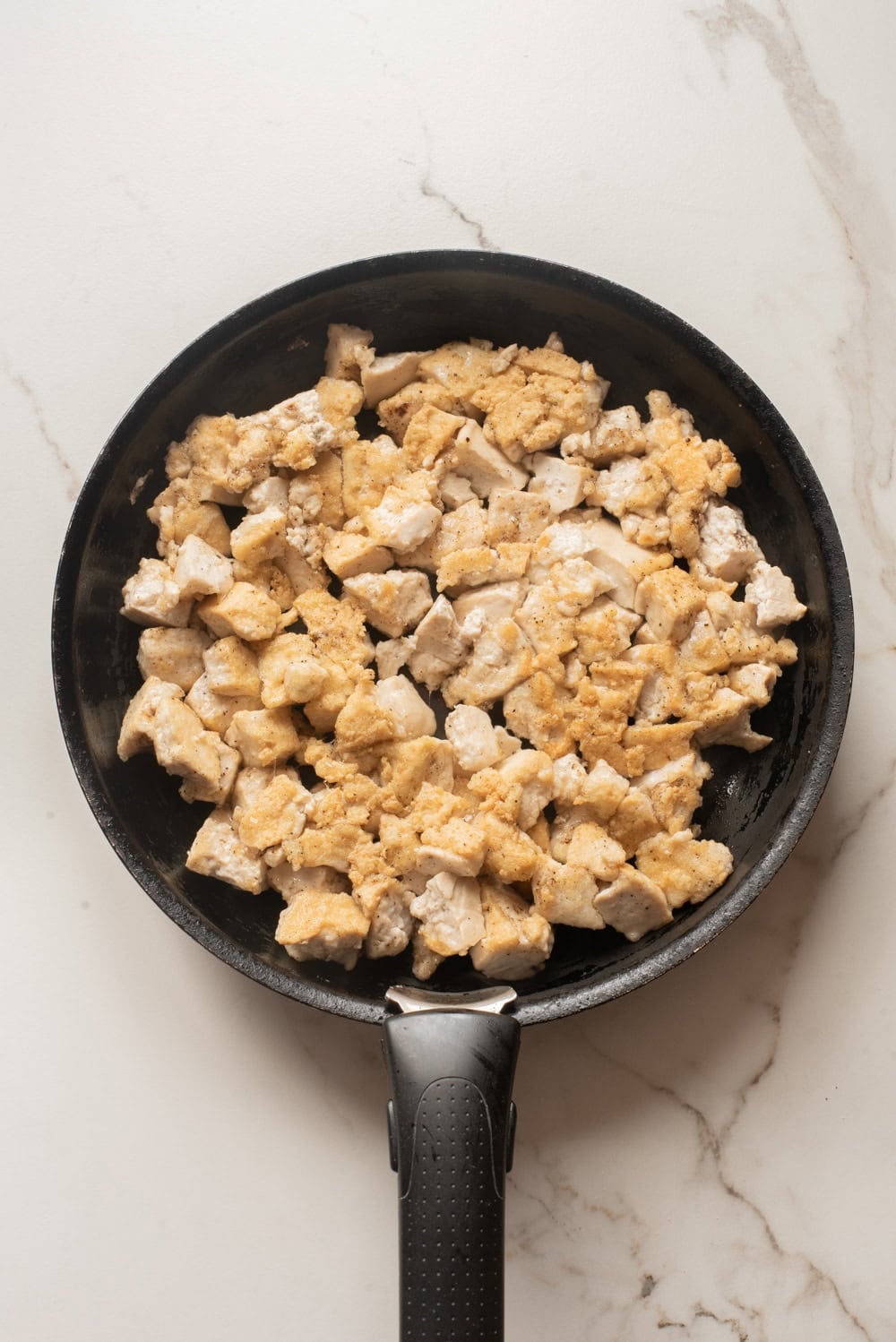 Torn tofu cooking in a skillet until golden and crisp.