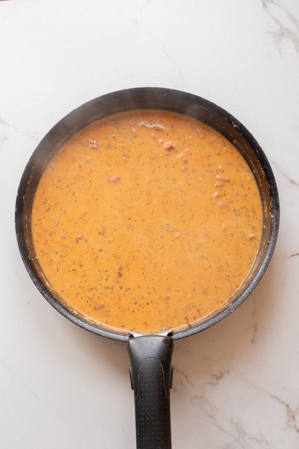 Creamy coconut tomato sauce simmering in a skillet.