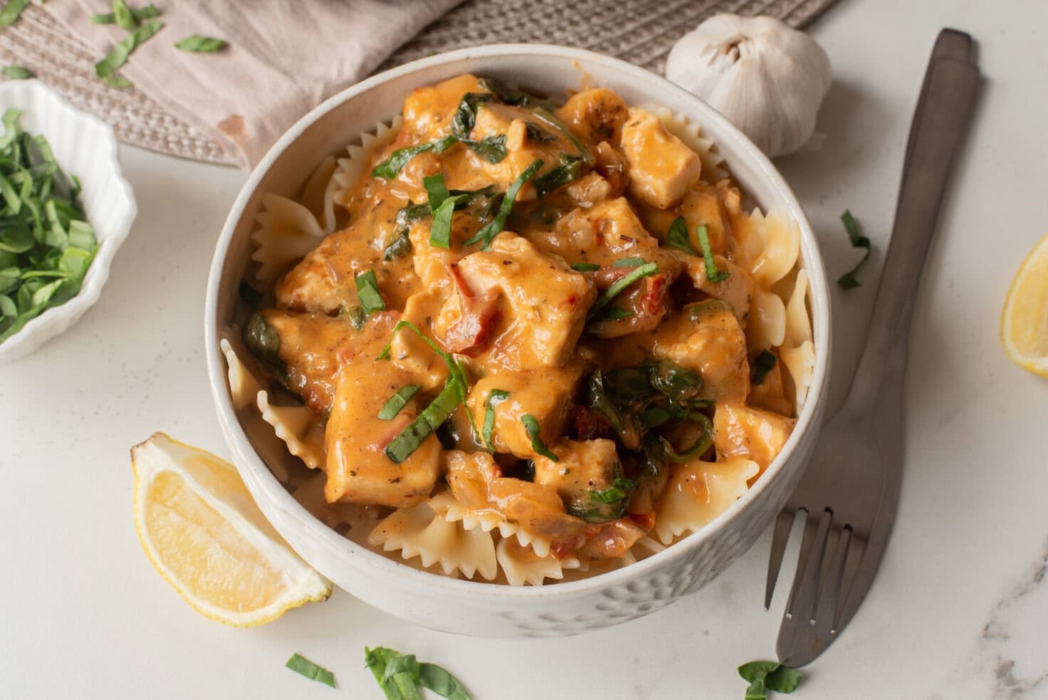 Bowl of creamy Marry Me Tofu served over pasta with fresh basil.