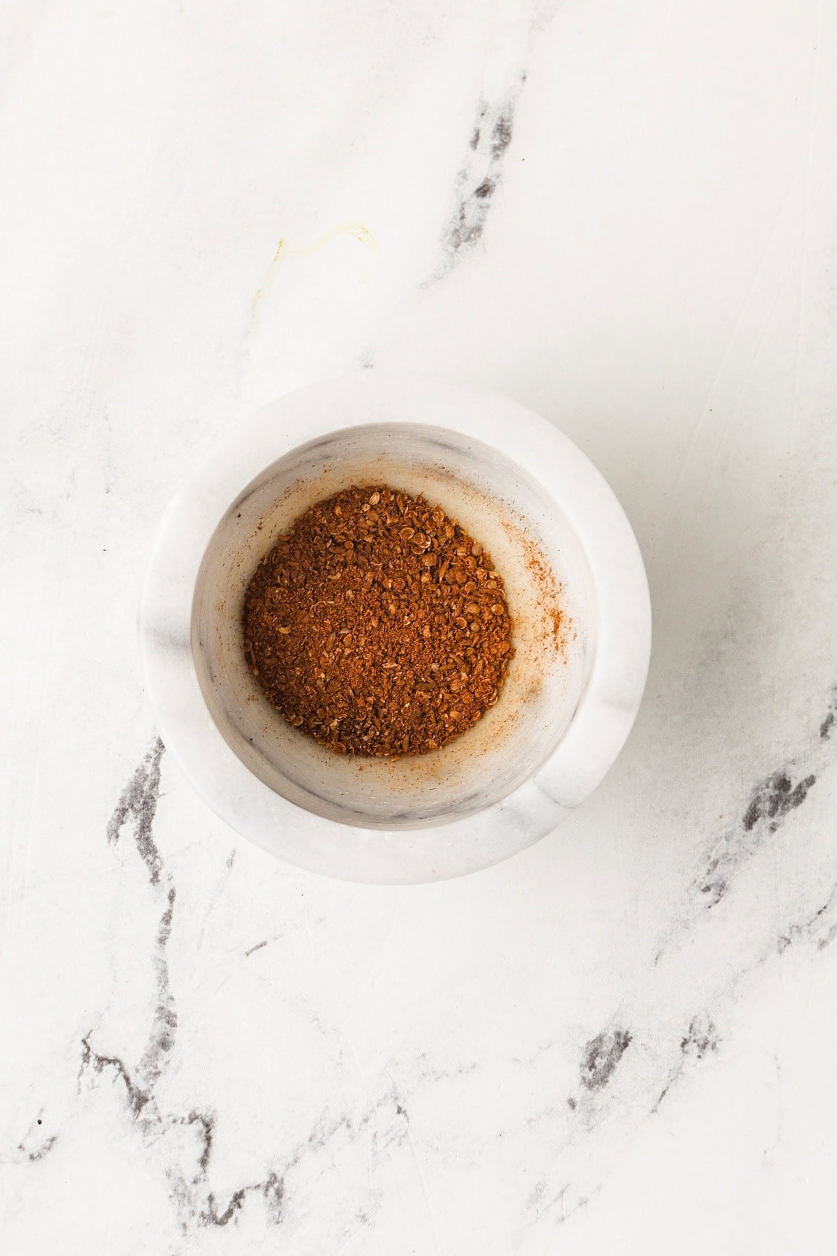Freshly ground spice blend for massaman curry paste in a mortar.