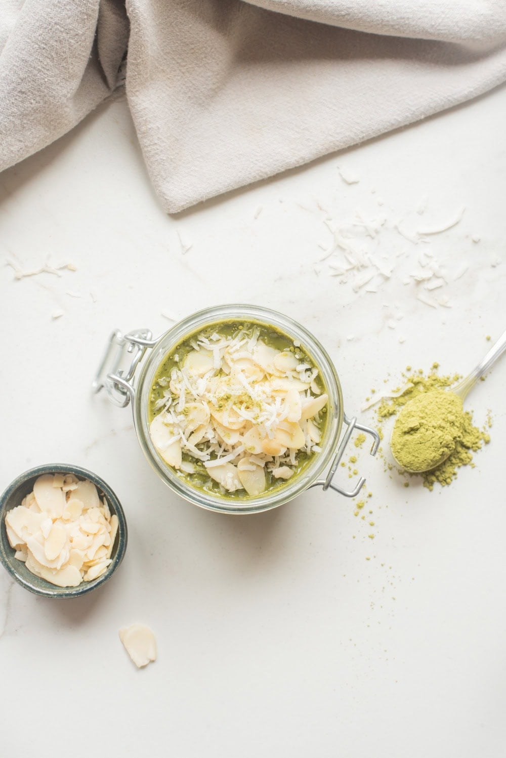 Overhead image of chilled matcha chia overnight oats with toppings in a jar.