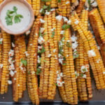 An overhead image of corn ribs with cheese sauce on the side.