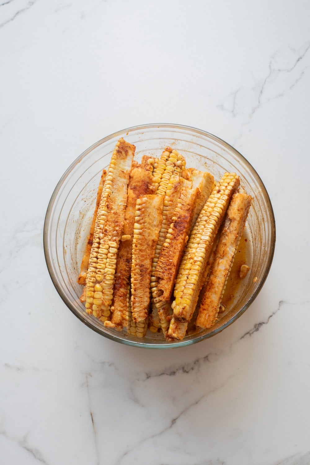 An overhead image of seasoning the corn ribs.