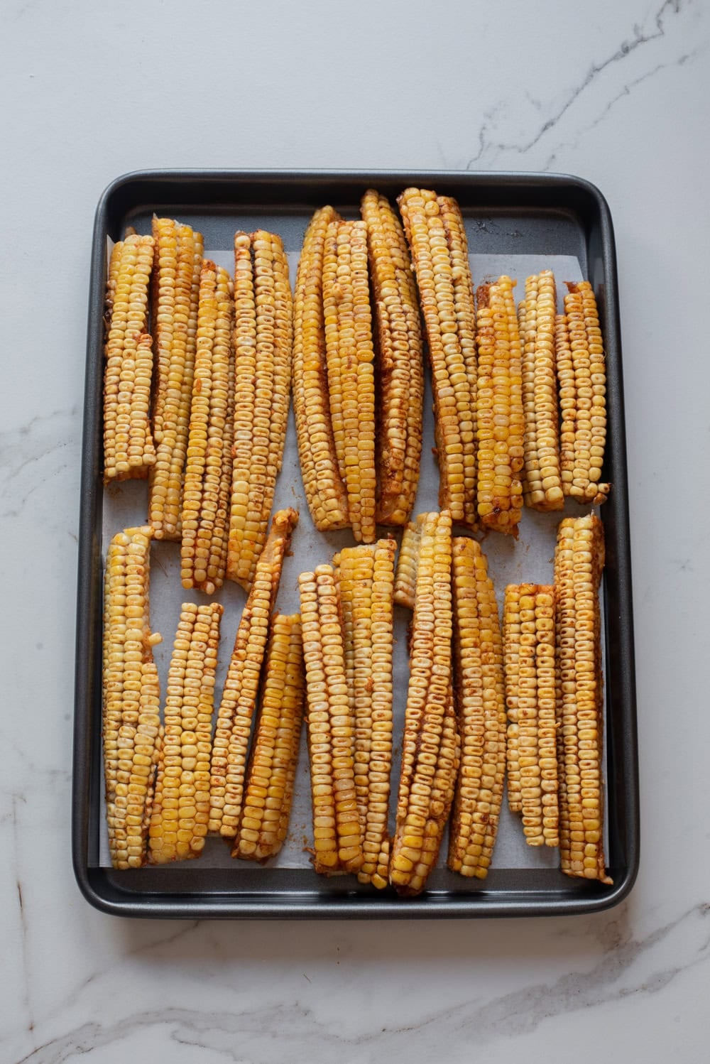 An overhead image of corn ribs on a baking sheet.