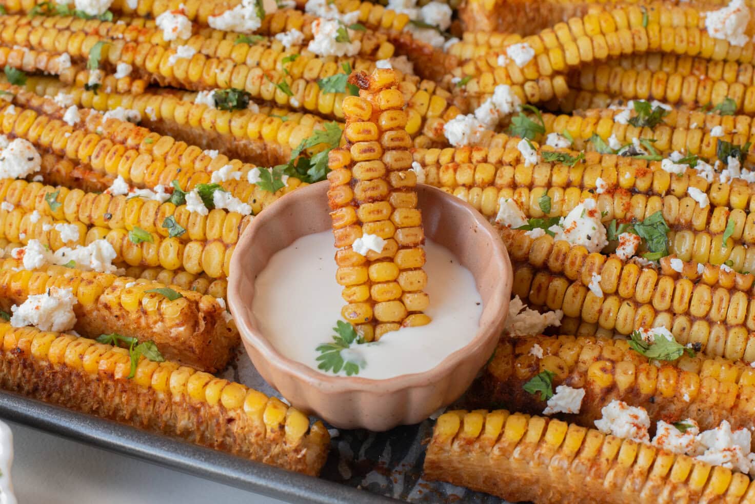 A close up image of dipping corn ribs in the sauce.