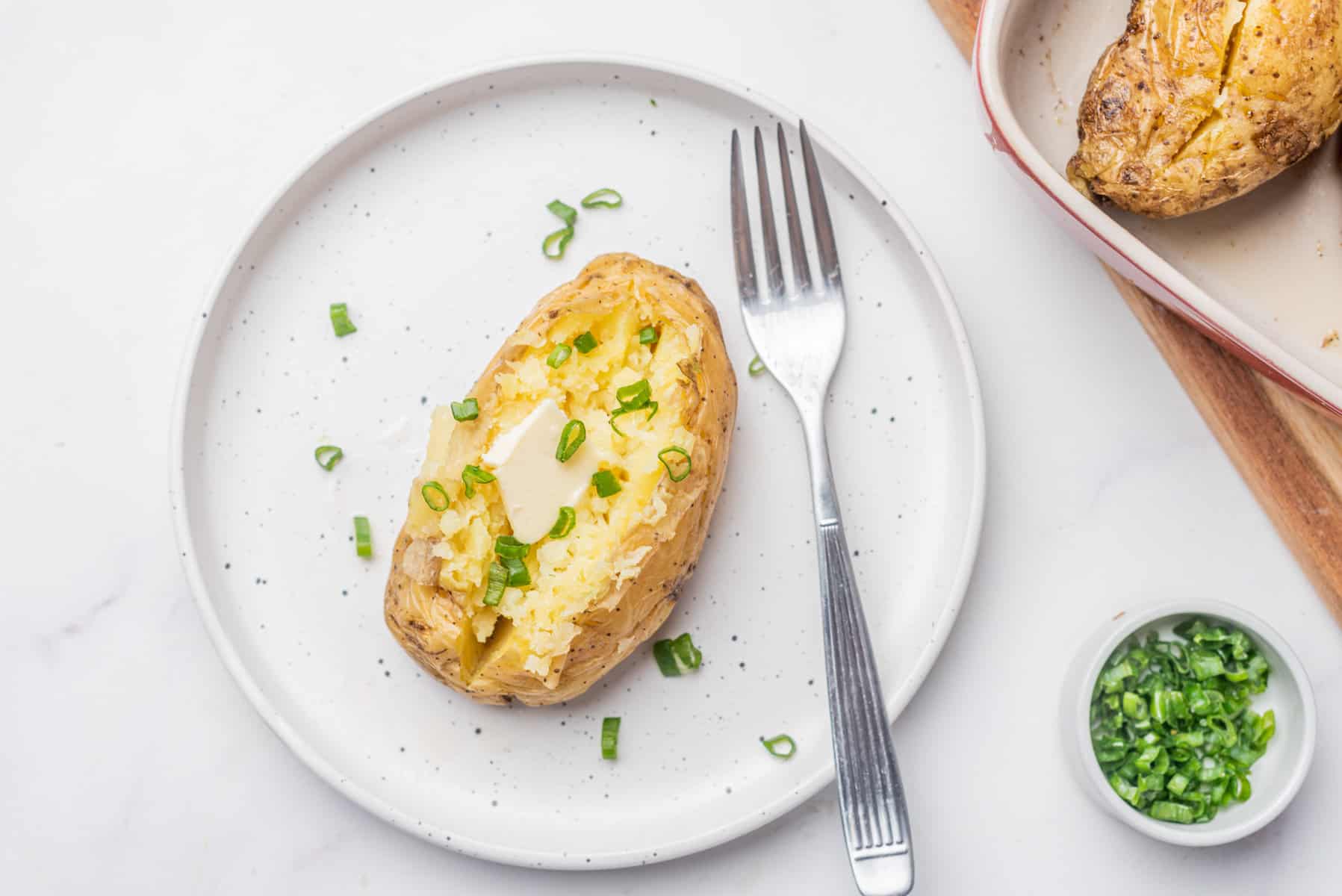 An overhead image of microwave baked potato on a plate with a fork