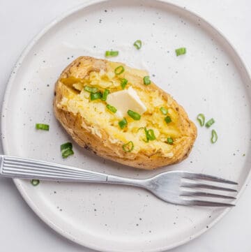 An overhead image of microwave baked potato on a plate with a fork