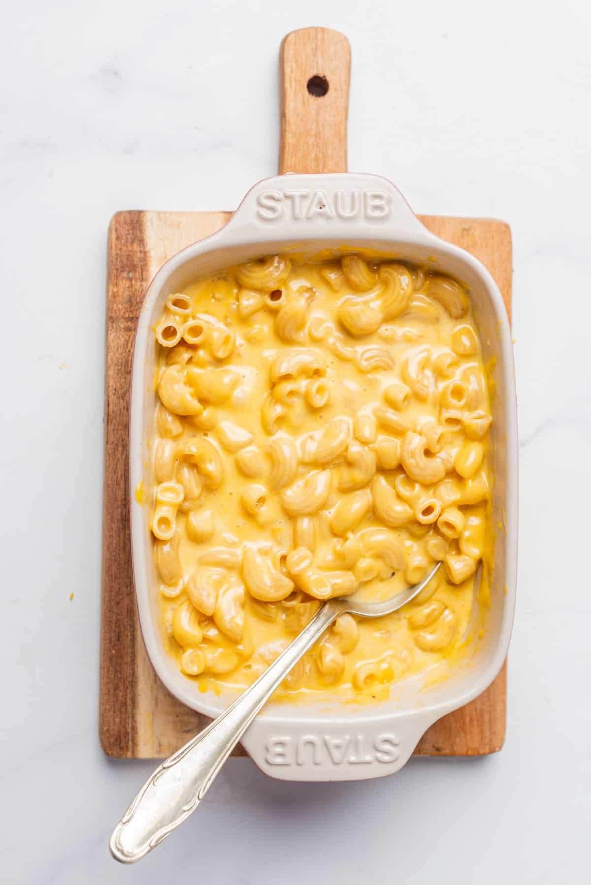 An overhead image of microwave mac and cheese in a serving platter with a serving spoon.