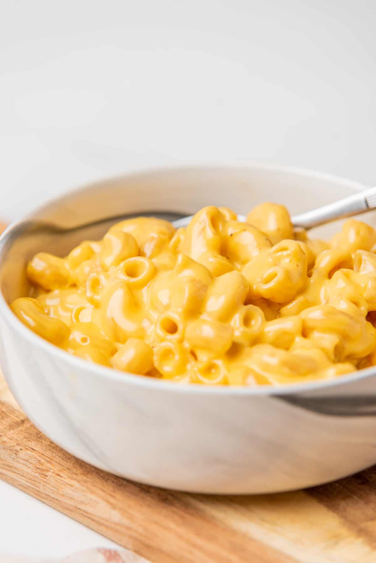 A closeup image of microwave mac and cheese in a bowl with a spoon.