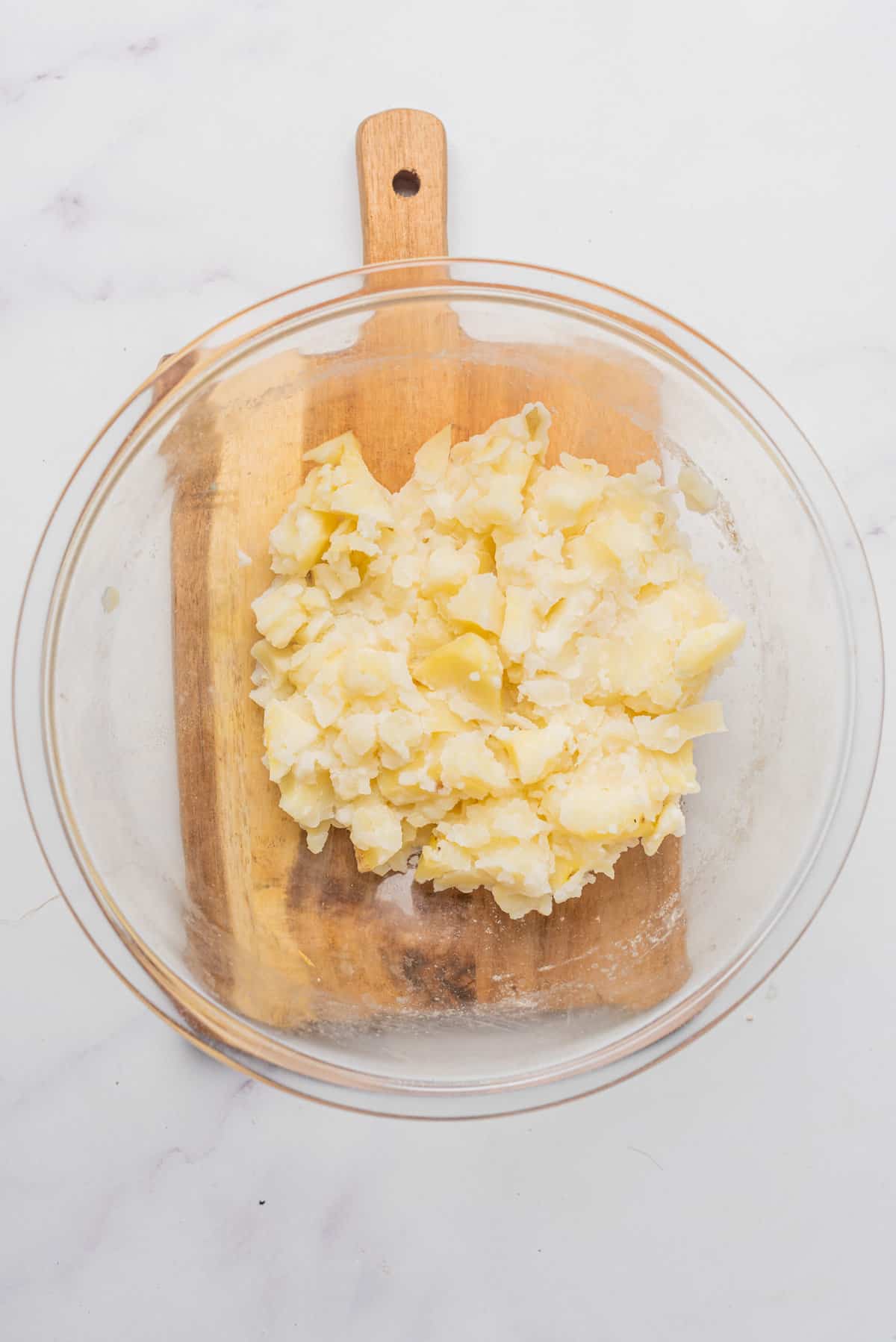 An overhead image of mashed potatoes in a bowl with butter.
