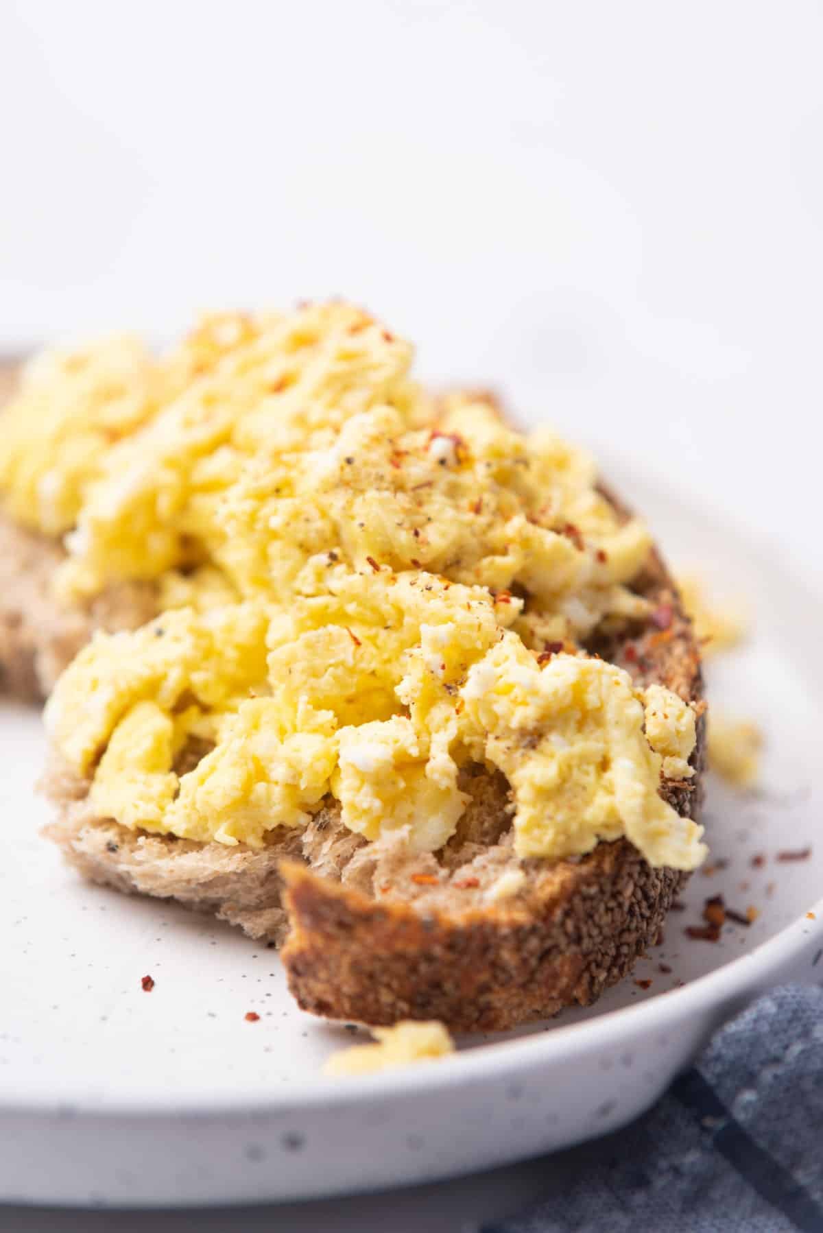 A closeup image of microwave scrambled eggs on a toast served on a plate.