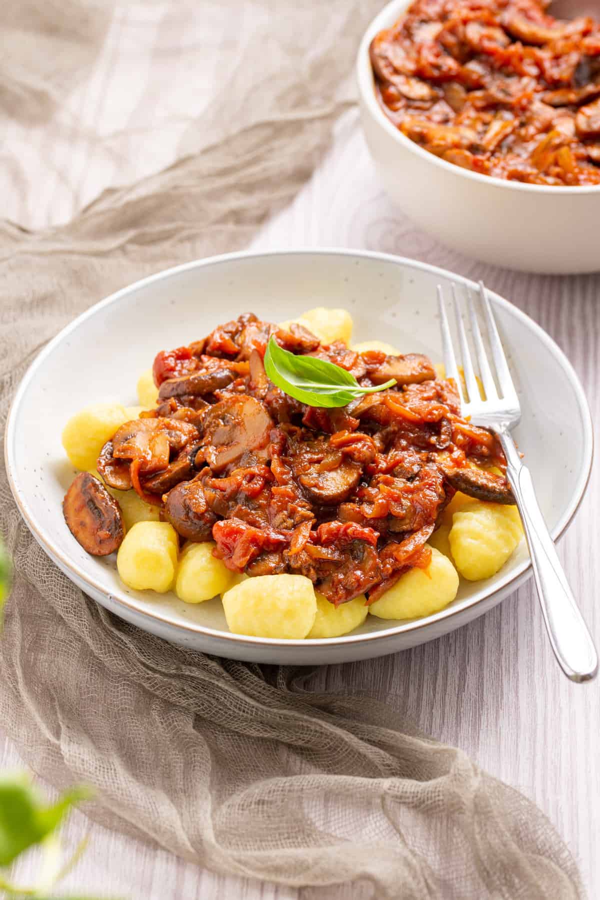 An image of mushroom ragu on top of gnocchi with a fork on the side.