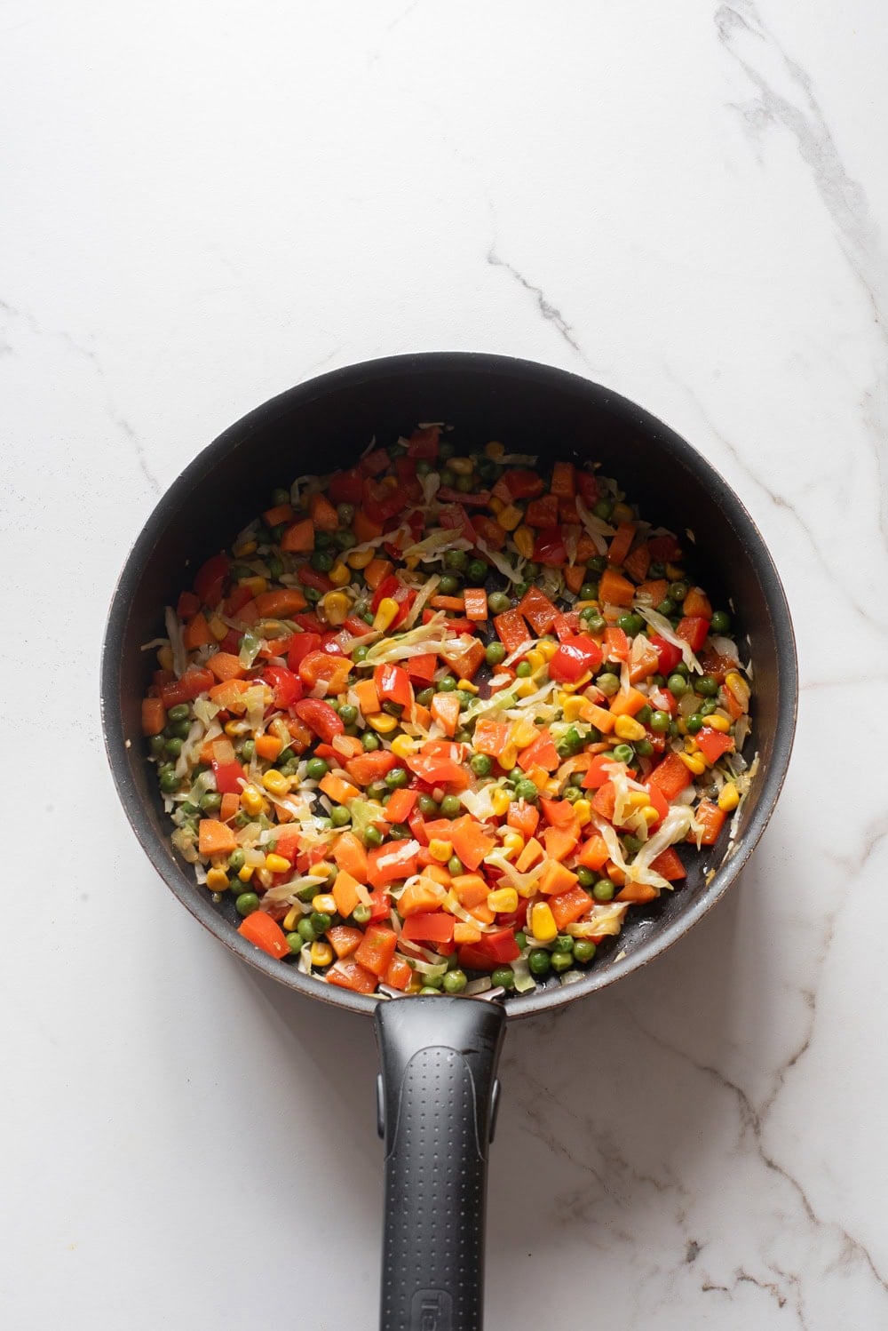 Mixed vegetables stir-frying in a skillet.