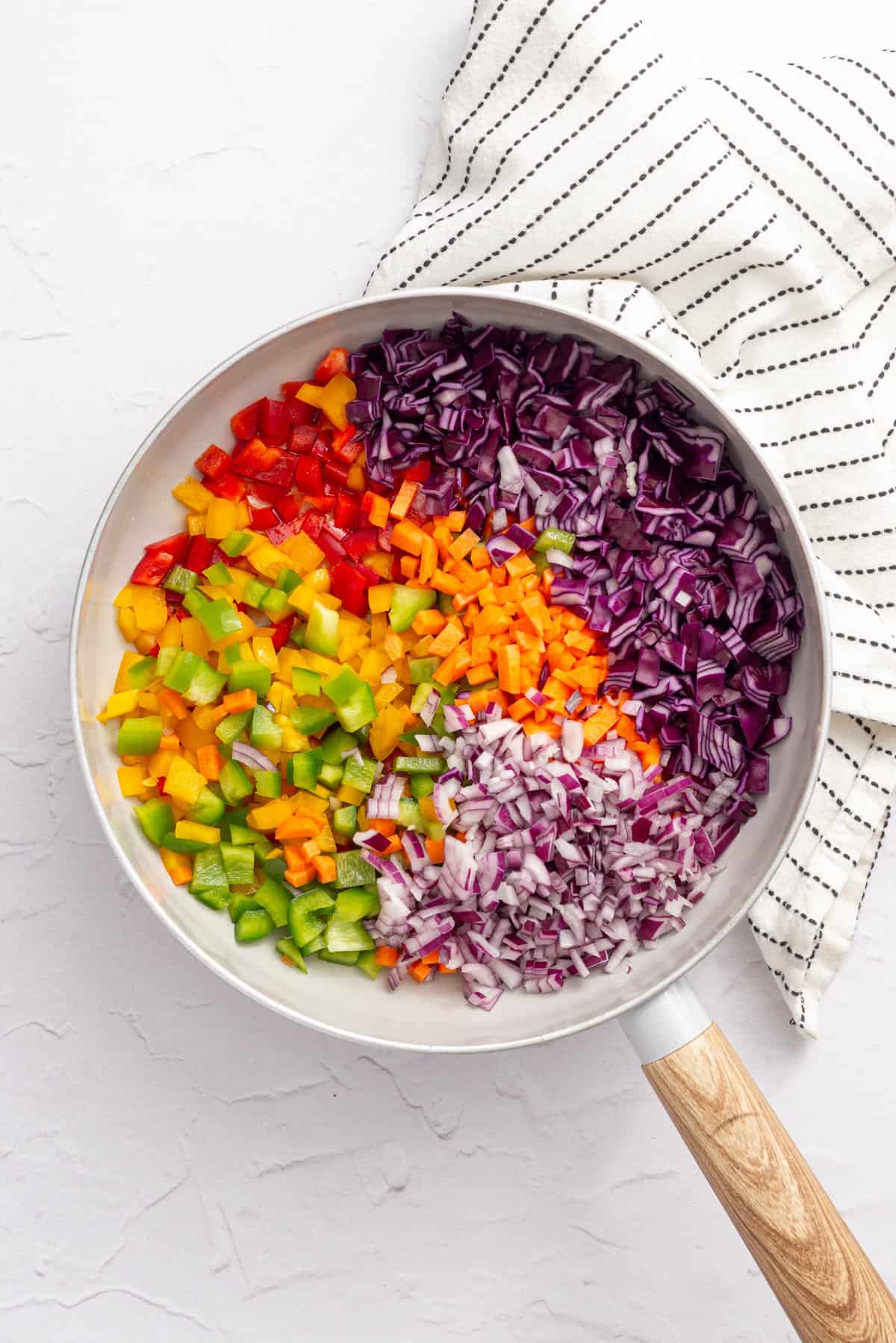 An overhead image of chopped fresh vegetables in a pan, before cooking.