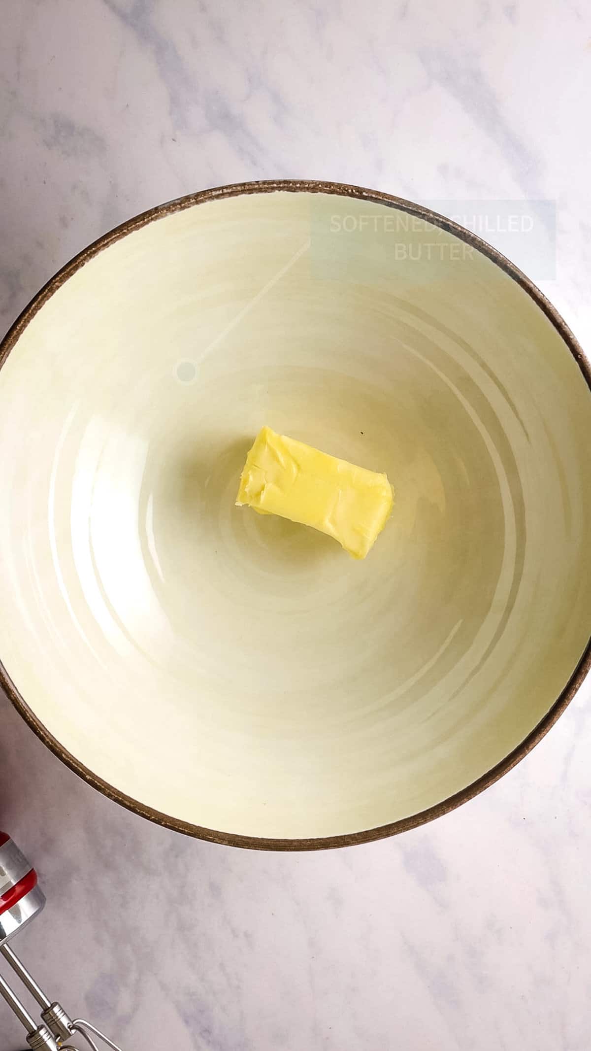 Overhead view of stick of butter in mixing bowl. 