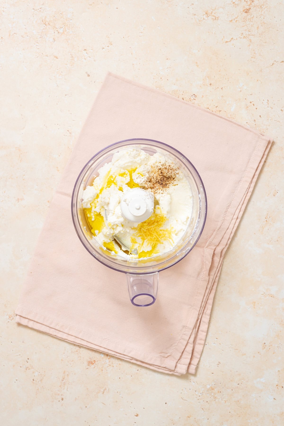 Ricotta, olive oil, lemon zest, and seasonings in a food processor before blending into whipped lemon ricotta.