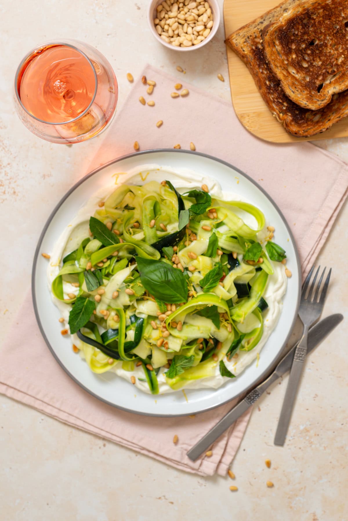 Finished zucchini ribbon salad with whipped ricotta, herbs, lemon zest, and toasted pine nuts plated for serving.